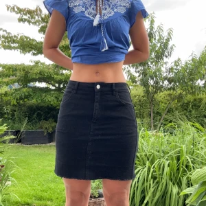 Svart jeanskjol  - Svart kort jeanskjol med fransig kant nertill och fickor baktill. Kjolen har dragkedja och knapp framtill samt bälteshällor. Enkel och stilren modell som är lätt att matcha till olika looks. Hör gärna av dig för fler bilder/frågor!😁☀️🌸