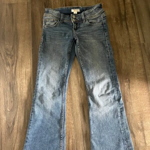 Blå bootcut jeans Gina Tricot - Snygga blå jeans från Gina Tricot i klassisk bootcut-modell. Jeansen har fem fickor, normal passform och coola slitningar framtill. Tillverkade i mjukt denimtyg med dragkedja och knapp. Perfekta för dig som gillar en avslappnad och trendig look. Obs på bild nummer 4 ser ni en fläck men den är väldigt liten och påverkar inte utseendet så mycket i hel het. Väldigt skönt material och super fina!💓