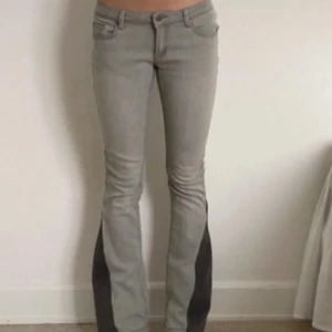 Grå bootcut jeans från Soaked in Luxury - Snygga grå jeans från Soaked in Luxury med bootcut-modell och mörkare grå paneler längs bensluten. Klassisk femficksdesign, bälteshällor och knappgylf. Jeansen har en modern passform och är perfekta för dig som gillar en unik twist på klassiska jeans.