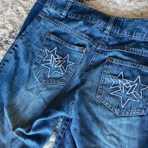 Blå jeans med låg midja  - Snygga vintage vita stjärnbroderier på fickorna. Skriv gärna vid frågor! 