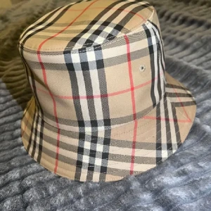 Burberry- hatt - Säljer min Burberry-hatt i väldigt fint skick. Den är knappt använd och ser nästan ny ut.  kvitto finns, Originalbox medföljer,  Inga skador eller fläckar.