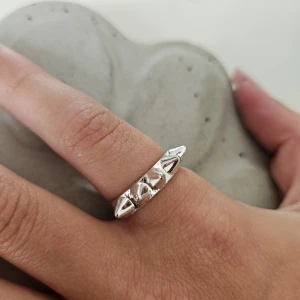 Silvrig ring med nitar - Cool ring i silverfärgad metall med fem spetsiga nitar runt ovansidan. Ringen har en edgy och unik design som sticker ut och passar perfekt för dig som gillar att addera lite attityd till din stil. Säljer denna eftersom den inte kommer till användning 