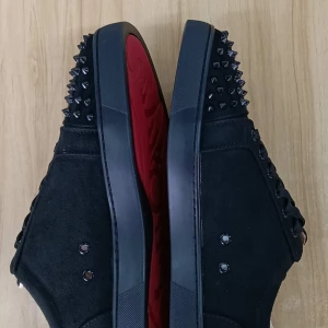 Helt nya Christian Louboutin svarta sneakers med nitar - Svarta sneakers i mocka från Christian Louboutin med coola svarta nitar på tån och klassisk röd sula. Skorna har snörning och en rund tå, vilket ger en edgy och lyxig vibe. Perfekta för dig som vill sticka ut med en exklusiv streetstyle. Har aldrig använts och är helt nya. Kan gå ner i pris vid snabb affär