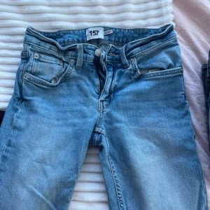 Bootcut jeans i ljusblå denim från lager 157 - Bootcut jeans i ljusblå tvätt från lager 157, modell Low Boot. Klassisk femficksdesign, låg midja och full längd. Jeansen är tillverkade i bomull och har en snygg, lätt utsvängd passform nertill. Perfekta för dig som gillar retrovibbar och relaxed stil. Obs.. byxorna har krympt lite i tvätten så skulle nog säga att dom passar dig med ”short” längd!