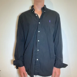 Svart Ralph Lauren Skjorta - Svart Ralph lauren skjorta || Storlek L (Slim Fit) || Skjortan är i bra skick || Modellen på bilden är 170cm och väger 62kg || Tveka inte på att höra av dig vid frågor eller funderingar 