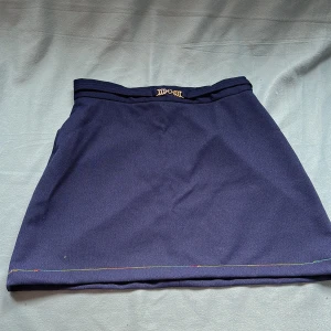 Marinblå miniskirt  - Supersöt mörkblå minikjol med färgglad söm längs kanten. Märkt som storlek 18 (UK) men midjan är ca 76 cm vilket motsvarar ungefär EU 38/M! Säljes pga för liten för mig. Väldigt fint skick 💙 