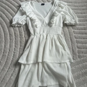 Vit volangklänning från Gina Tricot - Söt vit kortklänning från Gina Tricot med v-ringning, volangdetaljer och puffärmar. Använd en gång❤️