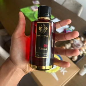 Mancera Red Tobacco parfym 120ml - Mancera Red Tobacco Eau de Parfum i en lyxig röd glasflaska med svarta och guldiga detaljer. Flaskan rymmer 120 ml och har en elegant svart kork. Doften är känd för sina intensiva och kryddiga noter med inslag av tobak.