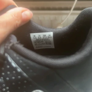 Svarta inomhusskor, Puma.  - Snygga svarta inomhusskor från Puma med vita detaljer och logga på tån. Skorna har snörning, perforerat mönster och vit platt sula med grepp. Sparsamt använda.