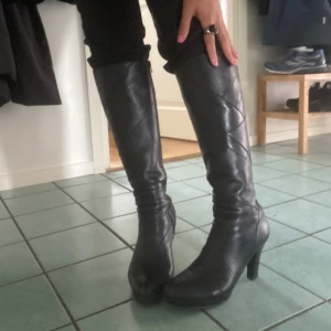 Svarta stövlar med klack - Snygga svarta stövlar i skinn med klack. Stövlarna går upp till knäet och har diskreta sömdetaljer längs skaftet. Perfekta för dig som vill ha en stilren och edgy look till höst och vinter!!! 🖤