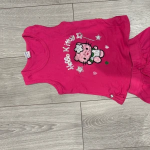 Hello Kitty rosa linnetopp barn - Supersöt rosa linnetopp från Hello Kitty med glittriga paljettdetaljer och tryck av Hello Kitty och stjärnor framtill. Toppen är ärmlös och har rund halsringning, perfekt för varma dagar. Matcha med shorts för en gullig sommarlook! Storleken har vi ingen aning om men vi skulle nog säga att det är storlek 110 (3-4 åringar)