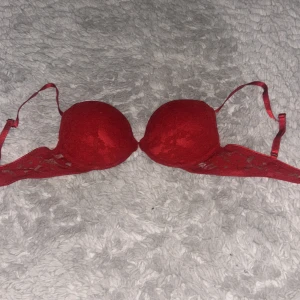 Röd spetsig bh - Snygg röd bhmed vadderade kupor och spetsdetaljer på sidorna med mjuk och stretchig känsla, perfekt för att ge en feminin touch till din outfit. Passar dig som vill ha något extra under en öppen topp eller klänning.