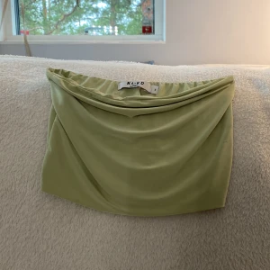 Ljusgrön bandeau tubtopp från NA-KD - Säljer en ljusgrön bandeau tubtopp från NA-KD. Toppen är axelbandslös och har en snygg draperad effekt framtill. Perfekt för dig som gillar minimalistisk stil och vill ha en enkel men trendig topp till sommaren. Och även aldrig använd!