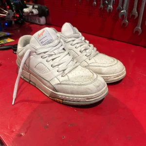 Vita sneakers från Axel Arigato - Snygga vita sneakers från Axel Arigato med klassisk låg siluett. Skorna har perforerade detaljer, rund tå och tjock sula med diskret logga på sidan och tungan. Tillverkade i skinn och textil, med vita snören och stilren design. Använda men i jätte bra skick, skickas såklart renare än på bilderna 