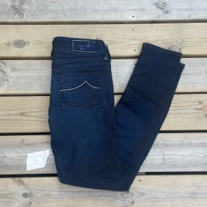 Jacob Cohen mörkblå skinny jeans (29-31) - Mörkblå jeans från Jacob Cohen med skinny passform. Klassisk femficksmodell med silverfärgade detaljer och snygg kontrastsöm på bakfickorna. Jeansen har normal midja och är tillverkade i stretchig bomullsdenim för en bekväm känsla. Sitter som 29-31 