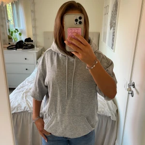 Grå hoodie med trekvarts ärmar  - Säljer en ljusgrå hoodie med trekvartsärmar och huva. Tröjan har snörning i halsen och en magficka framtill. Perfekt för en avslappnad och chill stil. Materialet är mjukt och skönt! Från hm och säljer för 95kr💕