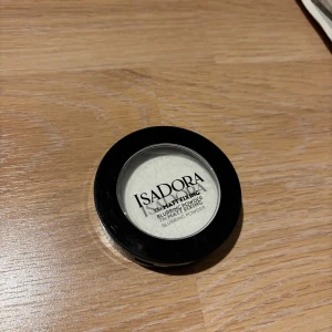 Isadora Matt Fixing Blurring Powder - Mattande transparent puder från Isadora i en rund svart dosa med genomskinligt lock. Perfekt för att fixera sminket och ge en slät, blurrad finish. Puderet är vitt men blir osynligt på huden och passar de flesta hudtoner. Den e oanvänd men har råkat sätta en nagel i den däravpriset se bild