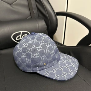 Blå Gucci keps med GG-mönster - Snygg blå keps från Gucci med ikoniskt GG-mönster över hela ytan. Kepsen är tillverkad i bomull och har justerbar rem baktill i blått läder. Perfekt för dig som vill sticka ut med en lyxig accessoar.
