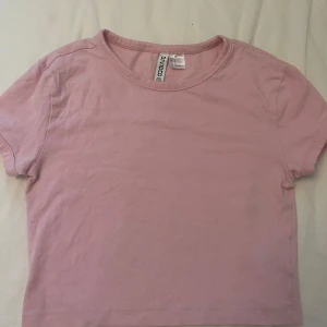 Rosa basic croppad topp - En enkel och söt rosa croppad topp med rund hals och korta ärmar. Köpt från H&M Divided och kommer inte mer till användning. Kontakta gärna innan köp!