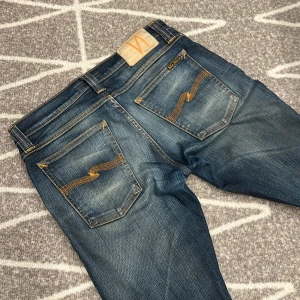 Nudie Jeans 29/30 - Säljer ett par blå slim fit jeans från Nudie Jeans i storlek 28/32 men sitter som 29/30. Jeansen har slitningar med en schysst tvättad look.