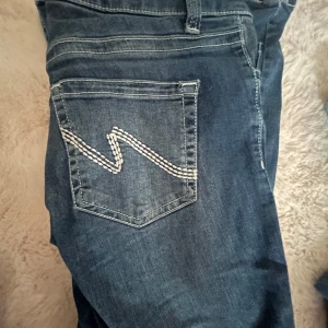 Blå jeans från Nelly med vit söm - Snygga blå jeans från Molly med cool vit zigzag-söm på bakfickan och dubbla knappar fram. Bra skick
