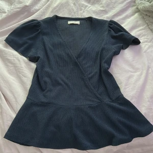 Mörkblå omlottblus Holly & Whyte XS - Supersnygg mörkblå omlottblus från Holly & Whyte i storlek XS. Sitter fint i midjan och har en lite utsvängd nederdel. ☺️Perfekt att styla med jeans eller kjol! Använd fåtal gånger💕pris går att diskuteras vid snabb affär