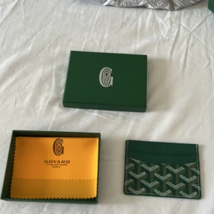 G plånbok - Snygg och stilren i grön  med deras ikoniska mönster. Plånboken har flera kortfack och är tillverkad i skinn med tryckt logga framtill. Perfekt för dig som vill ha något exklusivt och smidigt i fickan.  