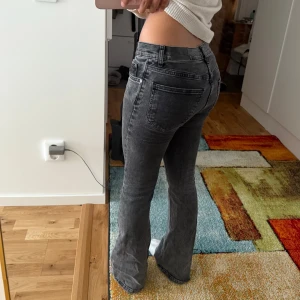 Gina Tricot Svarta Bootcut Jeans - Stilrena och bekväma jeans i mjuk denim med svart tvätt. Enligt Gina Tricot är modellen low waist, men de sitter snarare som mid waist. Märkta som storlek 36, men passar bättre en 34:a. Lite slitage längst ner på benen (se sista bilden). Perfekta jeans för dig som gillar både stil och komfort!❤️