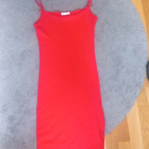 Röd kort klänning från Amisu - Snygg röd klänning från Amisu med smala axelband och figurnära passform. Enkel och stilren design som passar perfekt till varma dagar. Mjuk och stretchig känsla i materialet, vilket gör den superbekväm att bära.