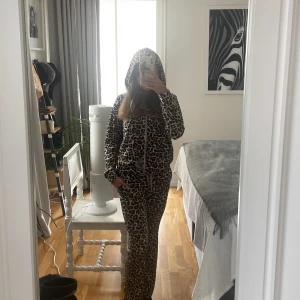 Leopardmönstrad hoodie och mjukisbyxa  från Lindex - Säljer en leopardmönstrad hoodie och mjukisbyxa från Lindex i mjuk polyester. Tröjan har huva, långa ärmar och dragsko framtill. Perfekt för dig som gillar djurmönster och vill sticka ut lite extra. Matcha med tillhörande byxor för en komplett look! Ord pris ca 500 kr