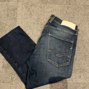 Replay Anbass slim jeans mörkblå - Snygga mörkblå Replay Anbass jeans i slim fit med klassisk femficksdesign och coola kontrastsömmar på bakfickan. Jeansen är tillverkade i stretchigt denim för extra komfort och har en stilren look som passar perfekt till sneakers eller boots.