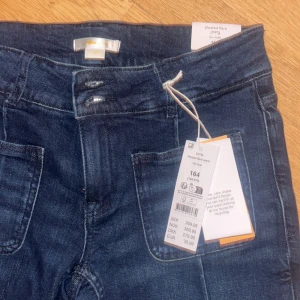 Mörkblå flare jeans med fickor - Snygga mörkblå jeans från Ginatricot med bootcut. Byxorna har stora framfickor och låg midja, perfekta för en trendig och avslappnad look. Tillverkade i mjukt jeansmaterial.