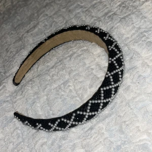 Gulligt svart diadem med pärlor - Ett svart diadem med rutigt mönster av små vita pärlor. Säljer eftersom att de inte passar på just mig och det är inte bara min stil❤️Använd typ 2-4 gånger, diademet ser nästan ut att vara nytt, köpte det för 129kr ungefär