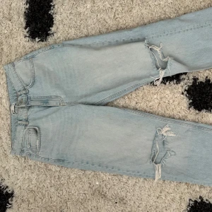 Ljusblå Jeans  - Säljer ett par ljusblå jeans från Gina  med snygga slitningar och hål på båda benen. 