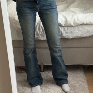 Blå bootcut jeans från Junkyard XS - Snygga blå jeans från Junkyard i bootcut-modell med klassisk femficksdesign och coola kontrastsömmar. Jeansen har medel/låg midja och är tillverkade i slitstarkt denim med dragkedja och knapp framtill. Jeansen är använda fåtal gånger och är i storlek xs, dom är bra i längd för mig som är 170 cm lång.