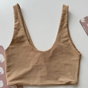 Beige linnetopp från Zara - Säljer en stilren beige kort linnetopp från Zara med djup rundad urringning och breda axelband. Toppen är i ett mjukt, stretchigt material som sitter skönt mot kroppen. 