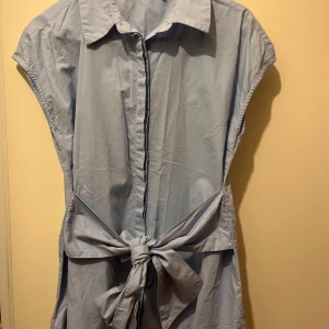 Skjorta strl 38 - Skjorta i strl 38 från NA-KD. Material: 100% bonull. Dolda knappar framtill och knytning i midjan.