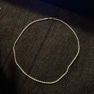 Tunn tvinnad silverfärgad halskedja - En stilren och tunn halskedja i silverfärg med tvinnad design. Perfekt för att bära ensam eller kombinera med andra smycken för en personlig look. Kedjan har ett enkelt lås och passar till många olika stilar. (ÄKTA SILVER)