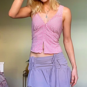Rutig rosa halterneck linnetopp - Supersöt rosa och vit rutig linnetopp med halterneck och knyt i nacken. Toppen har v-ringning, smock i ryggen och en liten slits framtill. Perfekt för varma dagar och ger en riktigt somrig vibe.