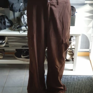 Bruna cargopants med raka ben - Säljer ett par bruna cargopants med raka, lite loose ben och stora fickor på sidorna. Byxorna har klassisk cargostil och är perfekta för en chill och avslappnad look. 