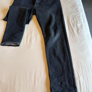 Svarta jeans Tiger of Sweden W36 L32 - Snygga svarta jeans från Tiger of Sweden i klassisk rak modell. Jeansen har fem fickor, diskreta sömmar och läderpatch med logga bak. Tillverkade i mjukt bomullsjeans-tyg som sitter skönt hela dagen.
