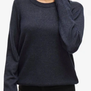 Mörkblå stickad tröja från Vila - Mysig mörkblå stickad tröja från Vila i klassisk modell. Tröjan har rund halsringning, långa ärmar och breda ribbade muddar vid ärmslut och nederkant. Perfekt för lager-på-lager och chill dagar.