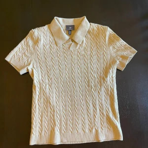 Pikétröja  - Kabelstickad pikétröja från H&M i beige med klassisk krage och korta ärmar. Tröjan har en snygg struktur med stickat mönster och regular fit. Perfekt för en preppy look och funkar året runt. Rekommenderar nu för en sommar date. 