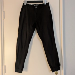 Svarta stretch chinos  - Svarta chinos i stretchigt bomullsmaterial. Modellen har resår i midjan och vid bensluten, sidfickor och bakfickor. Snygg och avslappnad passform som funkar till många olika stilar.