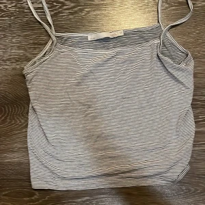 Randig linnetopp från 157, M - Säljer en smalrandig linnetopp från 157 i svart och vitt. Toppen har tunna axelband och är figurnära med en enkel, klassisk design. Perfekt för varma dagar eller som lager under en skjorta. Materialet är mjukt och stretchigt för en bekväm passform.