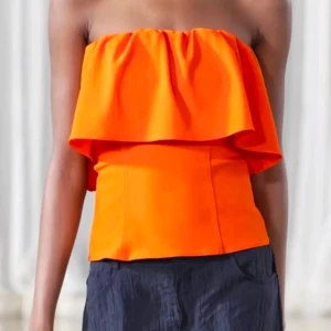 Orange bandeau tubtopp med volang - Hej säljer nu min populära tröja från zara Snygg orange axelbandslös tubtopp med bred volang upptill. Toppen har en figurnära passform och är perfekt för dig som vill sticka ut. Styla med jeans eller kjol för en trendig look. St M