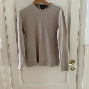 Beige merinoulltröja Polo Ralph Lauren - Säljer en stilren beige tröja från Polo Ralph Lauren i merinoull. Tröjan har rund halsringning, lång ärm och en slim fit-passform som sitter snyggt. Perfekt för dig som gillar klassisk och clean stil. Den har krymt lite så passar även S