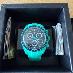 Omega x Swatch Speedmaster turkos - Säljer en Omega x Swatch Speedmaster med turkos boett och armband. Klockan har svart urtavla med tre subdials och vita detaljer. Tachymeter-skala runt bezeln och sportig design. Kommer i originalbox med tillbehör. Standardbanded medkommer såklart:) skriv om ni har några frågor eller funderingar 