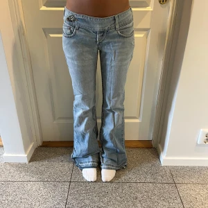 Ljusblå bootcut jeans lågmidjade  - Säljes dessa sååå snygga ljusblå jeansen, perfekt inför sommaren! Lågmidjade med detalj framtil. Har en liten slitning framtil men ingenting man tänker på. Midjemått : 37cm. Innerbenslängd :80 cm.