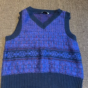 Blå stickad väst från COS - Snygg stickad väst från COS i mörkblå och lila toner med glittriga inslag. 